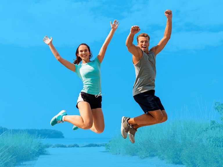 Zwei Jugendliche springen auf einem Strandzugang in die Luft
