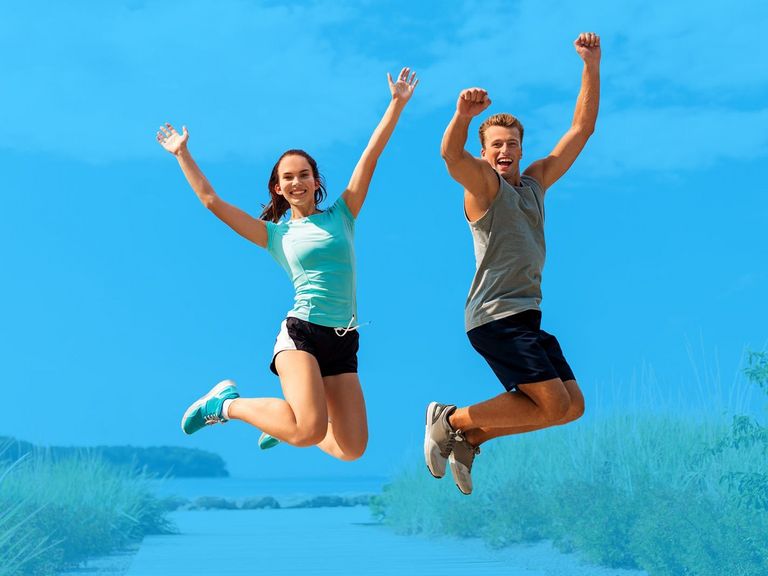 Zwei Jugendliche springen auf einem Strandzugang in die Luft