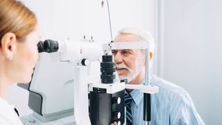 Versorgung bei Augenerkrankungen Augenärztin untersucht mit einem Spezialgerät die Augen eines älteren Mannes