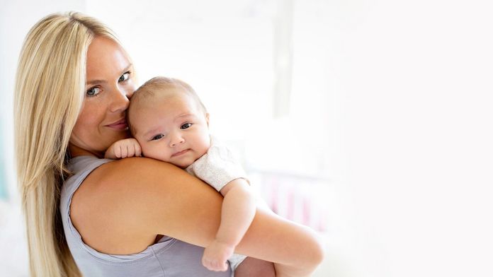 Mutter hält ihr Baby auf dem Arm und lächelt