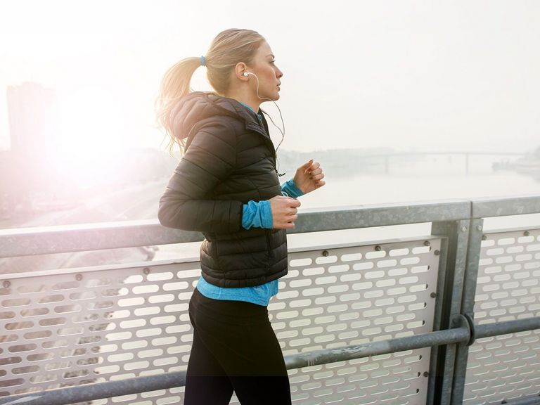 Junge Frau beim Joggen über eine Brücke