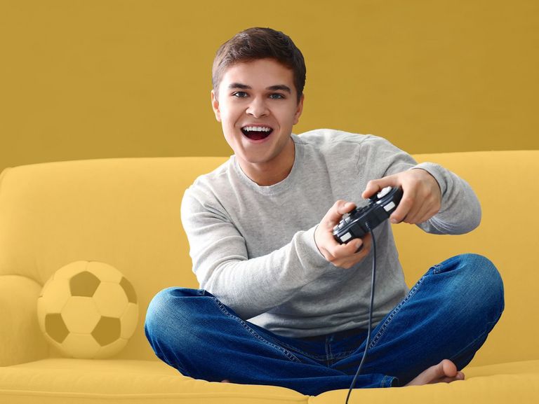 Teenager spielt mit einer Spielekonsole auf dem Sofa