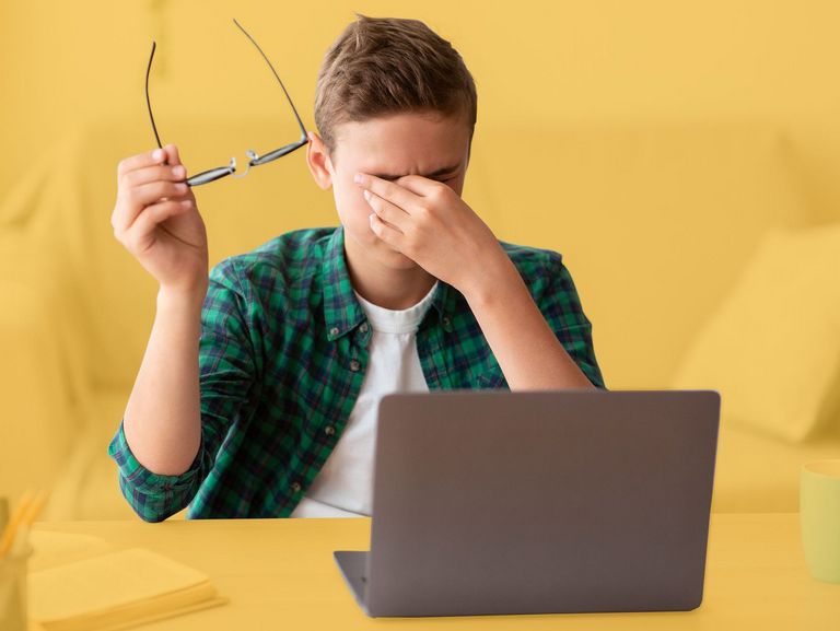 Teenager vor dem Laptop reibt sich die Augen
