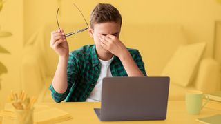 Teenager vor dem Laptop reibt sich die Augen
