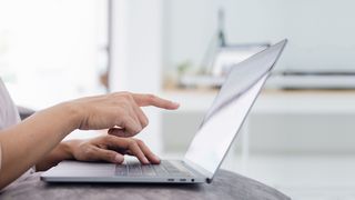 Frau zeigt mit dem Zeigefinger auf den Bildschirm eines Laptops