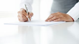 Eine Hand hält einen Stift und es werden auf einem Dokument Notizen gemacht