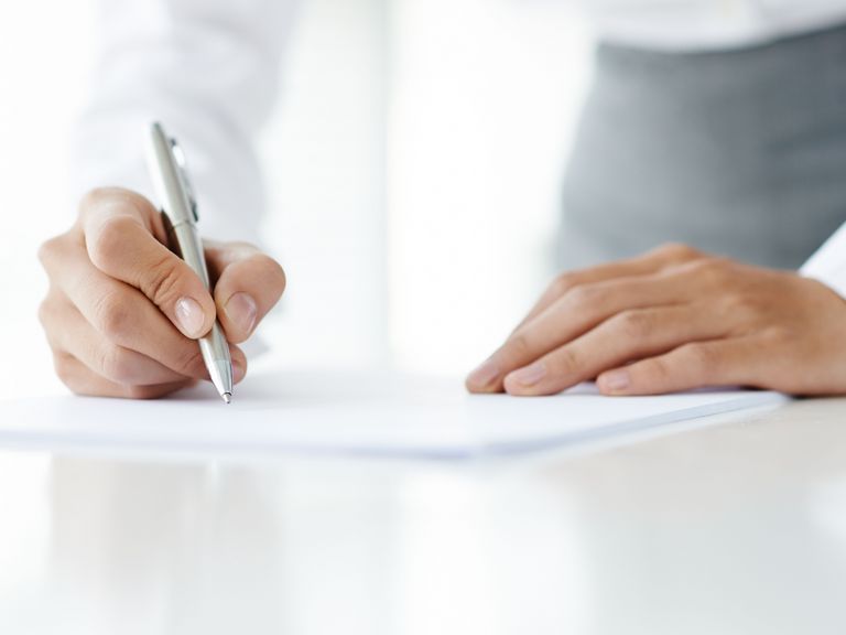 Eine Hand hält einen Stift und es werden auf einem Dokument Notizen gemacht