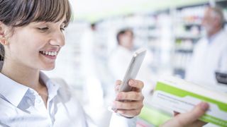 Frau scannt in der Apotheke ein Medikament mit ihrem Smartphone