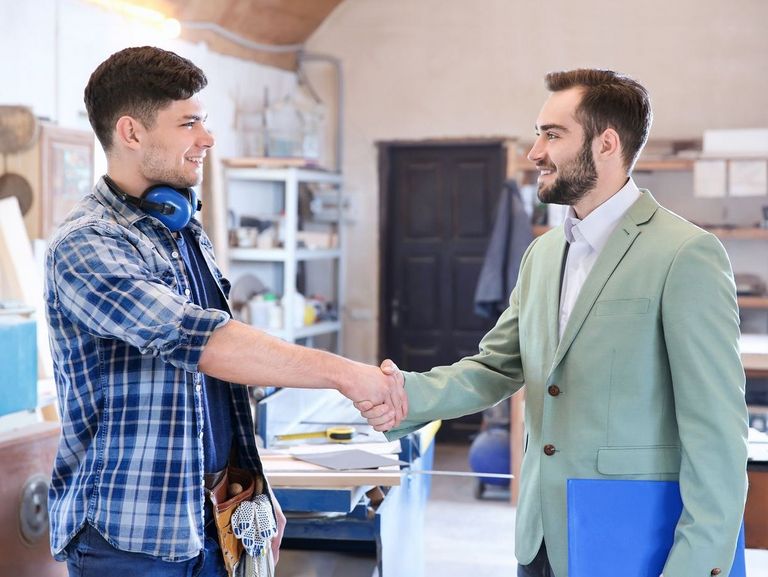 Handschlag vom Arbeitgeber mit seinem Azubi in einer Werkstatt