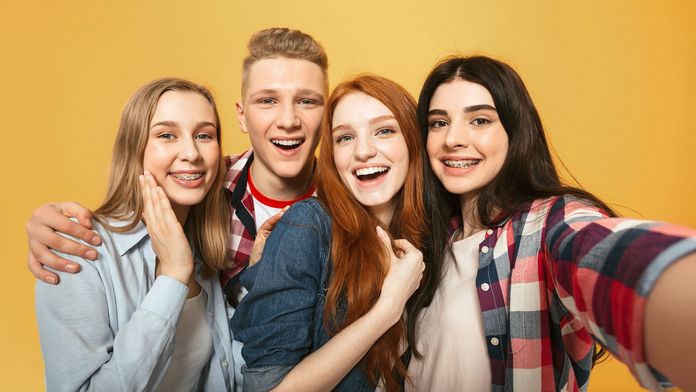 Vier Jugendliche schauen fröhlich in die Selfiekamera