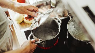 Gesunde Küche Mann am Herd mit zwei Töpfen