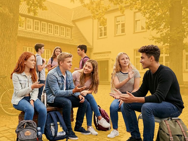 Eine Gruppe Jugendlicher sitzt auf dem Schulhof zusammen und ist ins Gespräch vertieft.