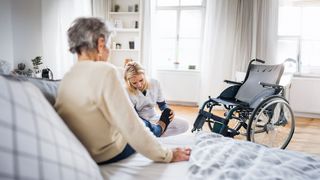 Pflegende Pflegende hilft einer Pflegebedürftigen beim Schuhe anziehen