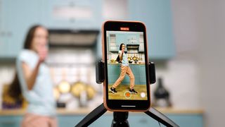 Frau in der Küche zeichnet einen Post für Instagram auf