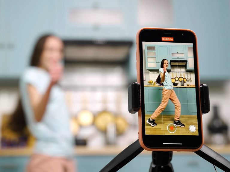 Frau in der Küche zeichnet einen Post für Instagram auf