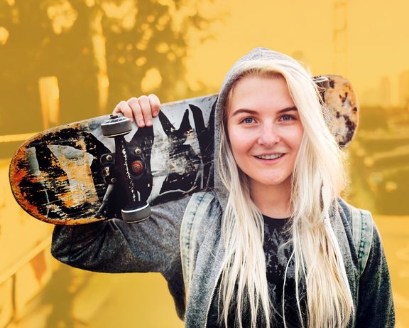 Skateboarding Junge blonde Frau mit Skateboard über der Schulter