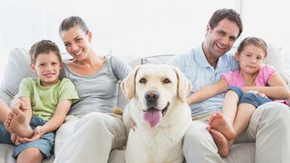 Glückliche Familie mit Hund in der Mitte