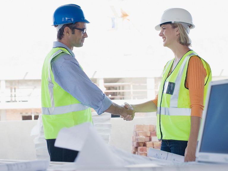 männlicher und weiblicher Mitarbeiter von Baufirma schütteln Hände