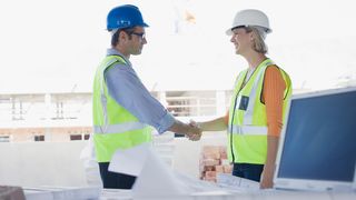 männlicher und weiblicher Mitarbeiter von Baufirma schütteln Hände