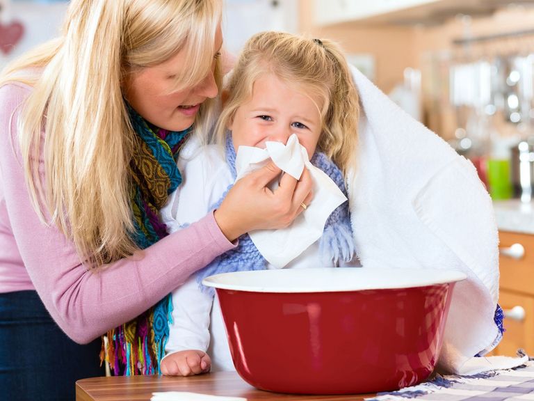 Mutter unterstützt ihre kleine Tochter beim Inhalieren über einer Schüssel