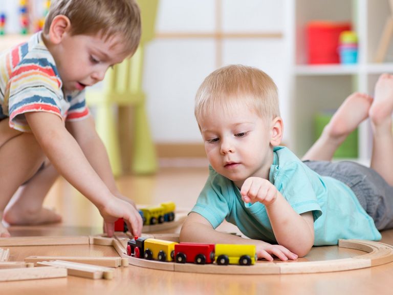 2 Jungen spielen auf dem Fußboden mit einer Eisenbahn
