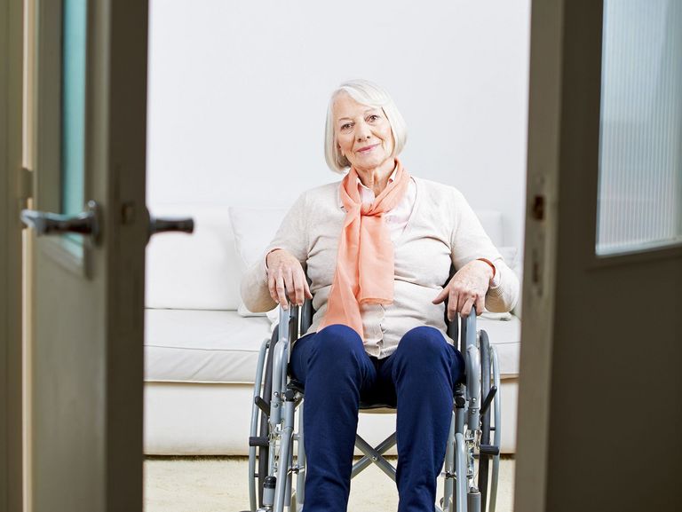Rentnerin im Rollstuhl vor einer Tür in ihrer Wohnung