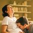 Mann küsst den Babybauch einer lachenden Frau