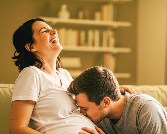 Bauchgefühlpaket Mann küsst den Babybauch einer lachenden Frau