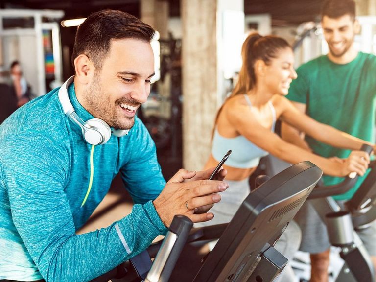 Mann im Sportdress sucht sich für sein Training die richtige Musik auf seinem Smartphone aus
