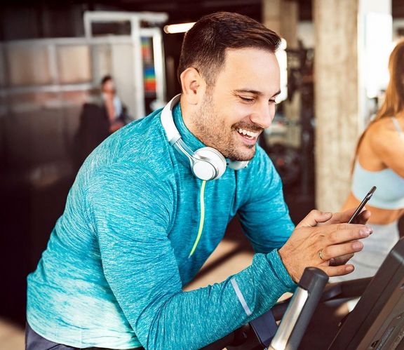 Mann im Sportdress sucht sich für sein Training die richtige Musik auf seinem Smartphone aus
