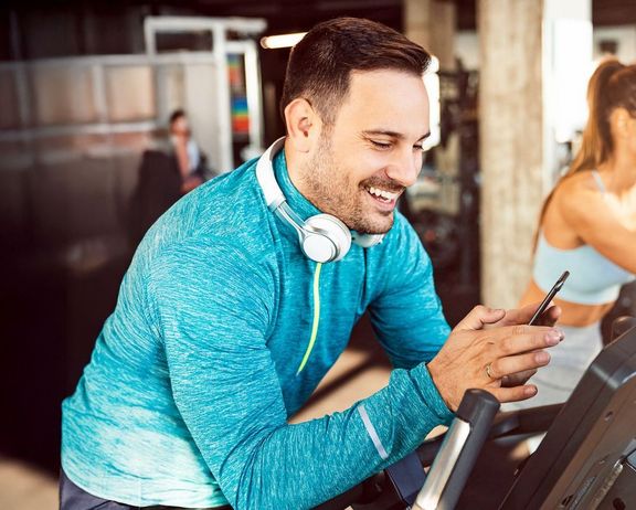 Mann im Sportdress sucht sich für sein Training die richtige Musik auf seinem Smartphone aus