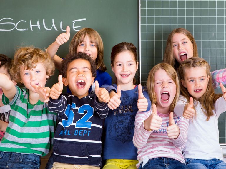 Schulkinder sitzen vor einer tafel und lachen