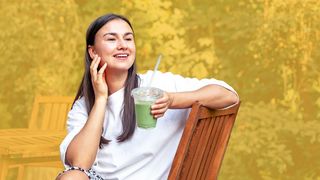 Matcha-Tee Junge lächelnde Frau hält einen Becher mit Matcha-Tee in der Hand