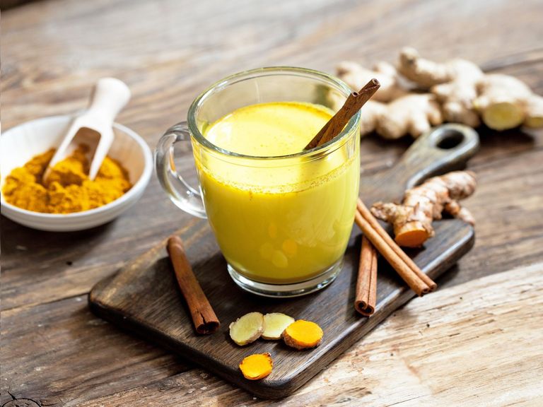 Goldene Milch in einer Glastasse auf einen dunklen Holztisch