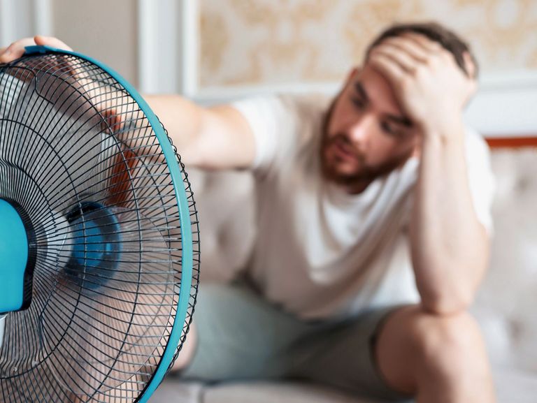 Mann im Wohnzimmer vor einem Ventilator sitzend