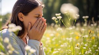 Heuschnupfen Frau in einem blühenden Feld sitzend niest in die Hände