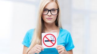Frau hält ein Rauchverbotsschild