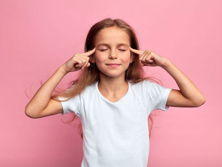 Mädchen schließt die Augen und legt die Zeigefinger an die Schläfen