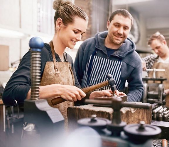 kleines Team an Mitarbeitern arbeitet mit Freude in einer Werkstatt