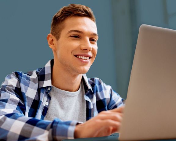 Schulabsolvent vor einem Laptop sitzend