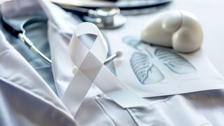 Arztkittel, Stethoskop und Bild einer Lunge auf einem Tisch