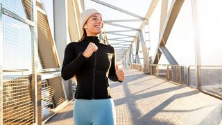 Junge Frau beim winterlichem Joggen über eine Brücke