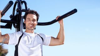 Mann nutzt ein Fitnessgerät für die Arme auf einem Trimm-dich-Pfad