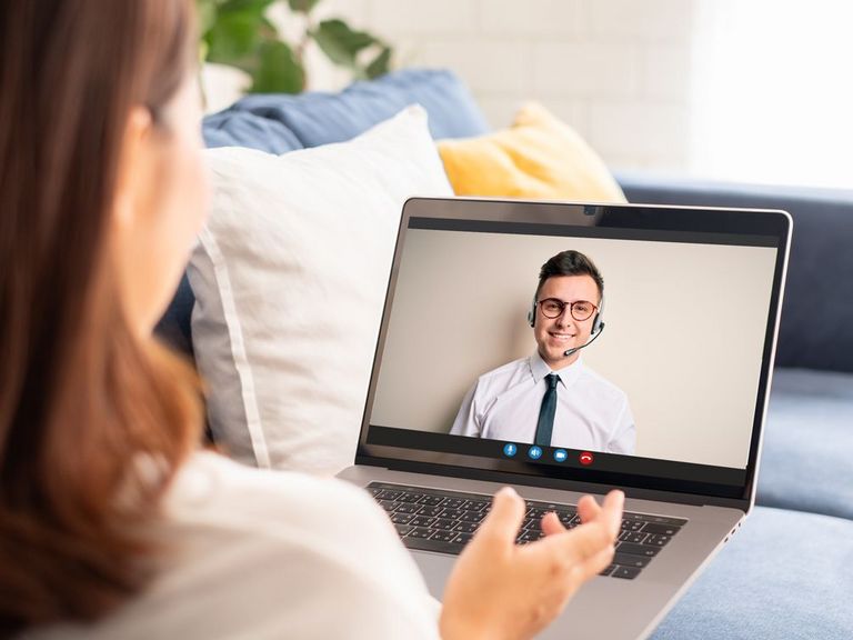 Frau sitzt auf dem heimischen Sofa und hat einen Videocall mit der Serviceberatung