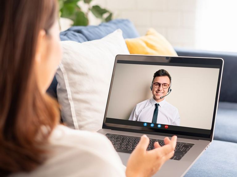 Frau sitzt auf dem heimischen Sofa und hat einen Videocall mit der Serviceberatung