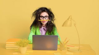 Schulstress Junge Frau mit Brille und zerzausten Haaren am Schreibtisch mit Laptop