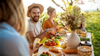Happy Food Freunde essen gemeinsam am Tisch im Freien