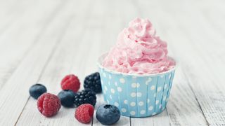 Frozen Joghurt in einem Pappbecher und dazu Beeren
