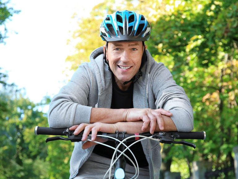 Mann mit Fahrradhelm stützt sich auf seinen Fahrradlenker