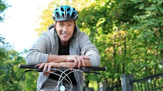 Sport Trotz Heuschnupfen Mann mit Fahrradhelm stützt sich auf seinen Fahrradlenker